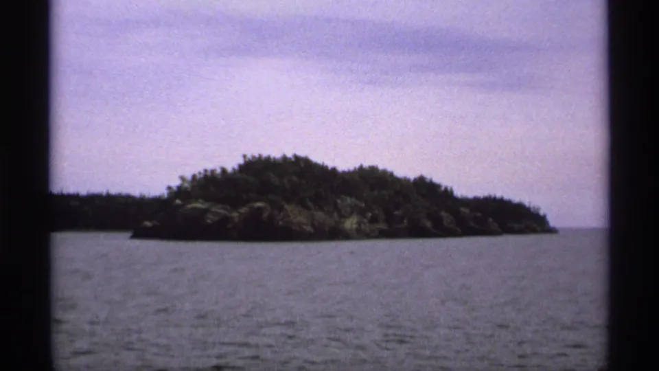 Small tree-covered island at Isle Royale, Michigan, filmed across open water on 8mm in 1971.