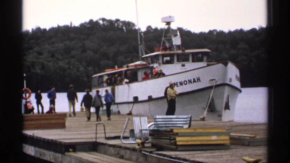 1971 Isle Royale frame showing the white boat PENONAH at a wooden dock, with passengers on the pier and forested shoreline behind it.