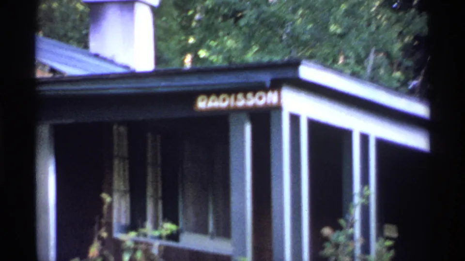 Close 1971 Isle Royale home-movie view of a building entrance with columns, plants, and a Radisson sign above the porch.