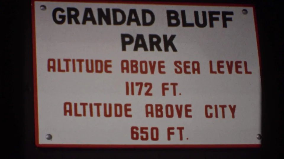 The Grandad Bluff Park sign fills the lower frame, naming the park and altitude figures with La Crosse winter bridge scenery beyond.