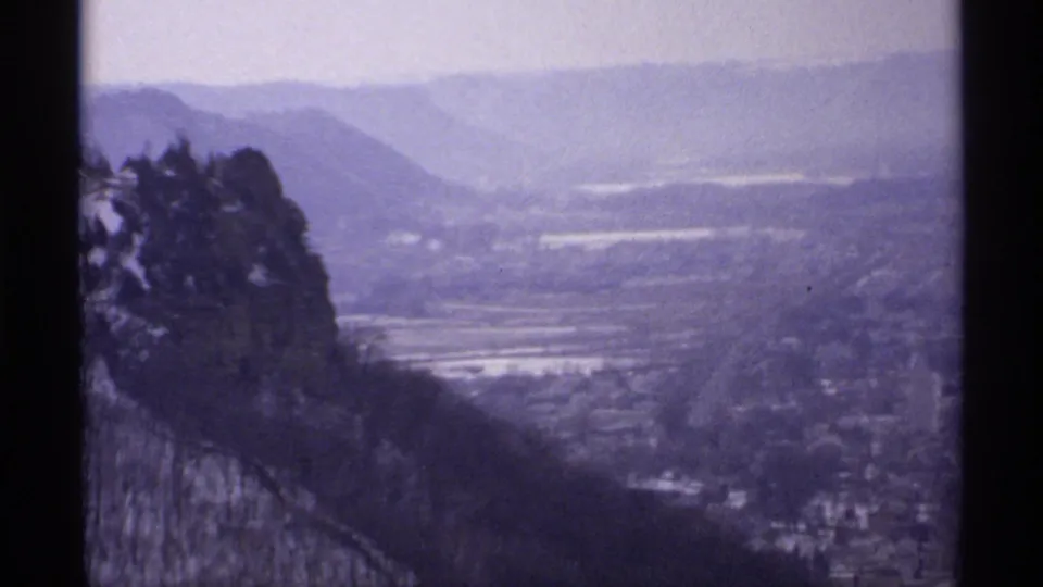1971 Grandad Bluff Park view over La Crosse, with rocky foreground, bare trees, valley floor, and distant hills.