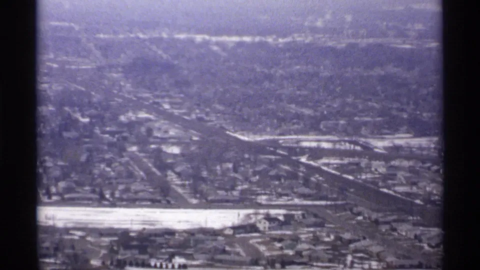 Aerial or high-vantage view of La Crosse, Wisconsin, showing neighborhoods, roads, a pale river corridor, and hills in 1971 footage.