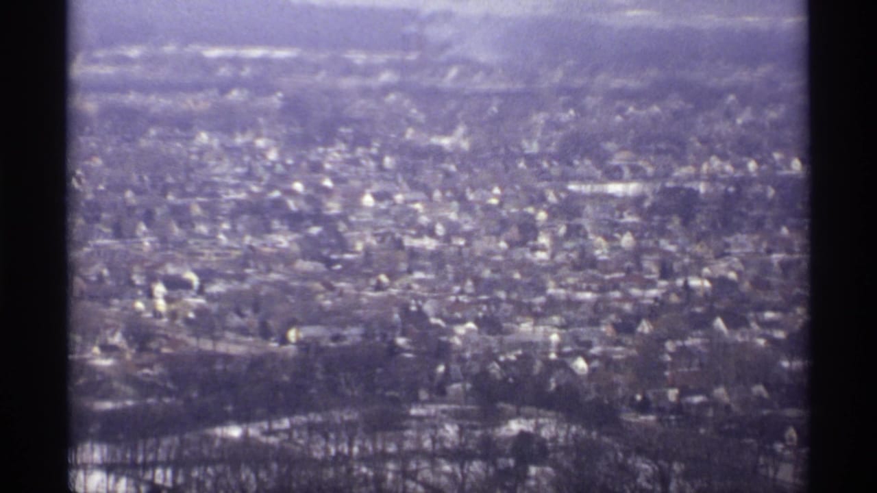 1971 La Crosse, Wisconsin aerial view showing a residential area with snow-dusted roofs, bare trees, and distant terrain.