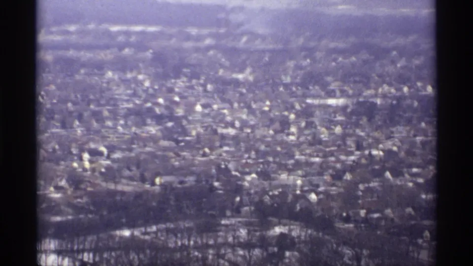 1971 La Crosse, Wisconsin aerial view showing a residential area with snow-dusted roofs, bare trees, and distant terrain.