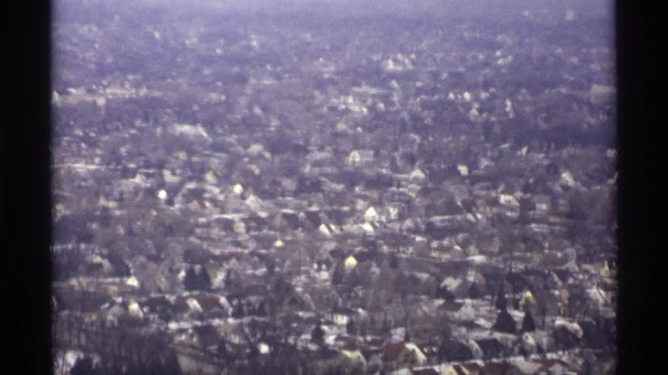 Soft 8mm aerial view of La Crosse residential streets with scattered houses, bare trees, and snowy ground patches.