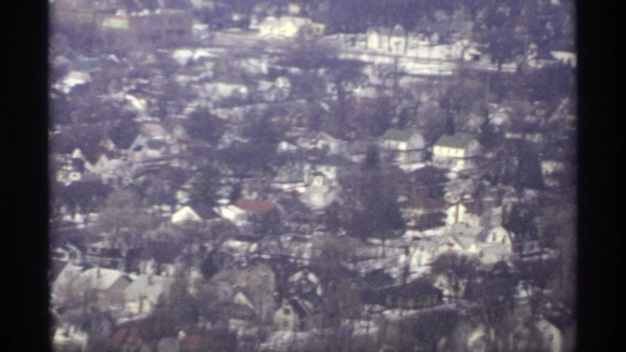 Aerial view of houses and bare trees with a dark vertical frame edge.