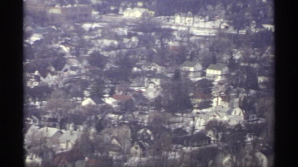 1971 La Crosse aerial view over residential houses, leafless trees, and streets, partly divided by a dark window or film frame edge.