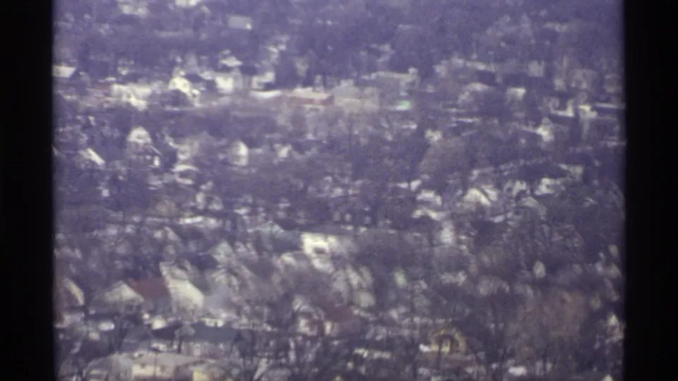 Aerial 8mm frame showing a La Crosse residential area in 1971, with houses set among bare trees and softened by purple film tint.