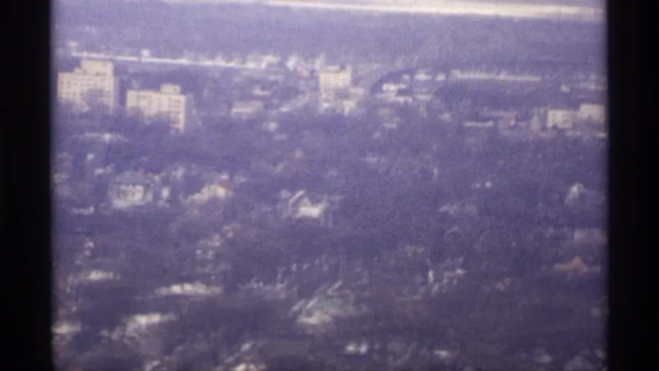1971 La Crosse aerial frame showing a soft, purple-cast view of neighborhoods, roads, trees, and distant urban structures.