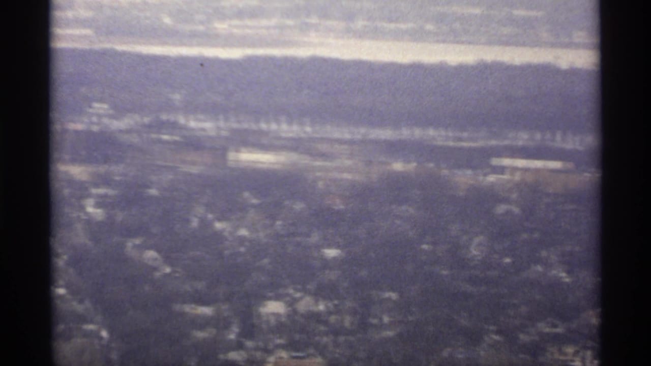 Hazy winter aerial view of a city beside water and distant bluffs.