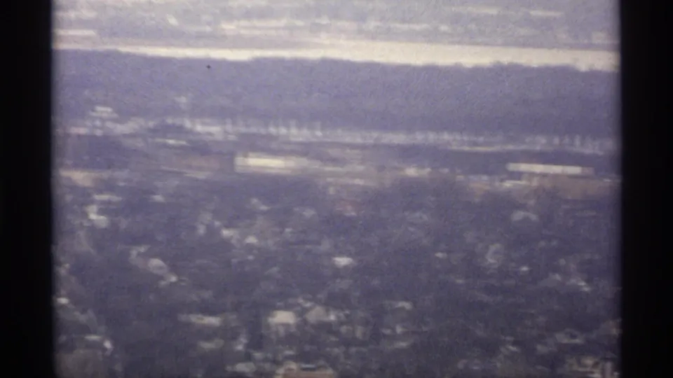 1971 La Crosse, Wisconsin aerial view showing snowy neighborhoods, distant water, and bluffs under a cloudy winter sky.