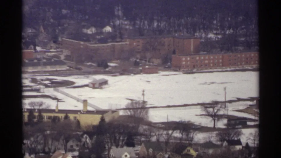 1971 La Crosse aerial view of large brick buildings, a snow-covered field or courtyard, and nearby houses.