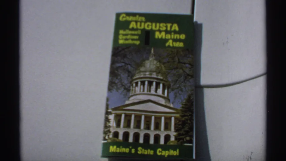 1971 Maine travel brochure held in view, with Hallowell, Gardiner, Winthrop, and Maine's State Capitol text visible.