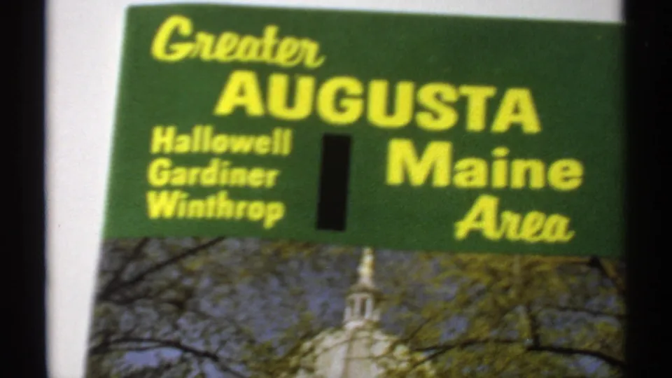 Soft 8mm close-up of the Greater Augusta Maine Area brochure, emphasizing yellow lettering and the capitol image.