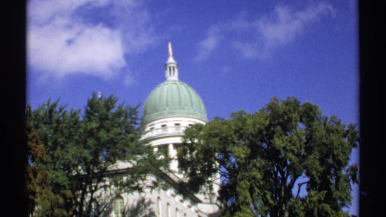 1971 Maine home-movie view of a green-domed public building, with trees obscuring part of the white facade.
