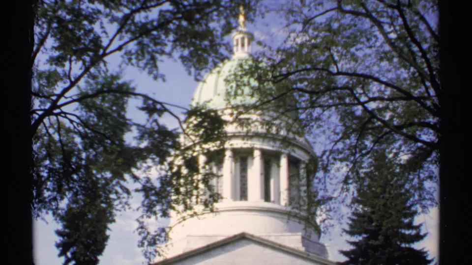 1971 Maine 8mm frame showing the white domed top of a public landmark with branches crossing the view.