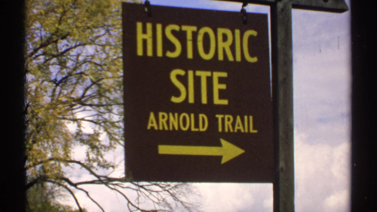 Historic Site Arnold Trail sign repeated in close view with trees and sky behind it.