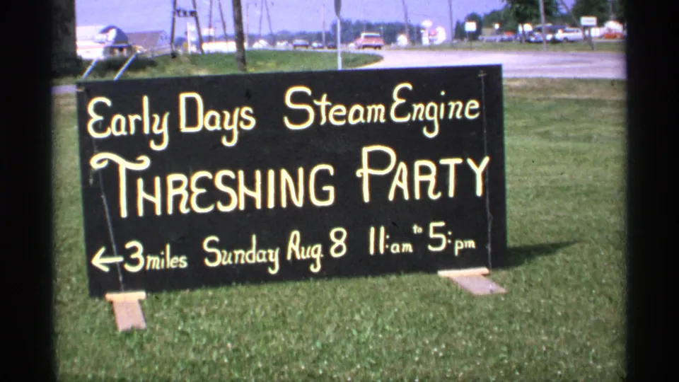 1971 Minnesota 8mm frame with the black Early Days Steam Engine Threshing Party sign cropped close in the foreground.