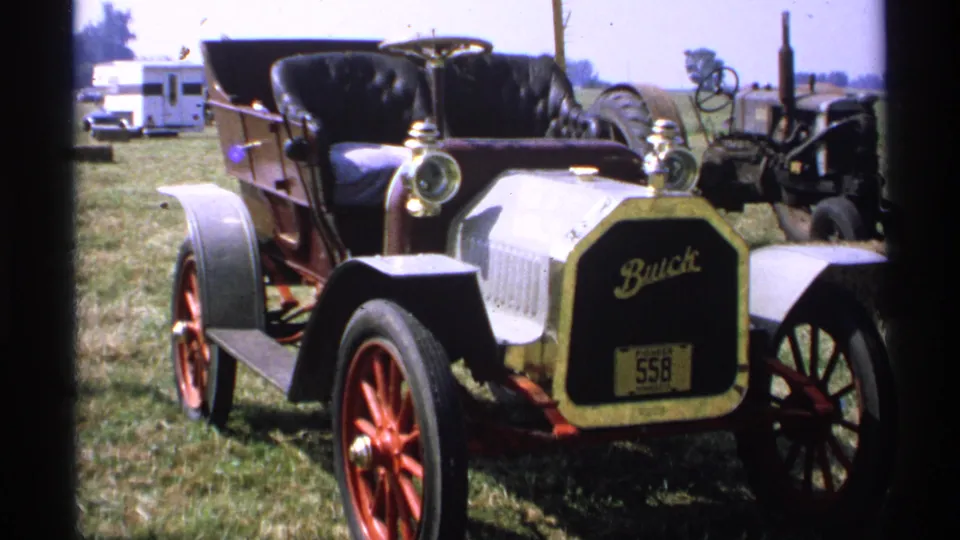 1971 Minnesota 8mm frame showing an early open Buick automobile at the steam-engine gathering, with machinery and a camper behind it.