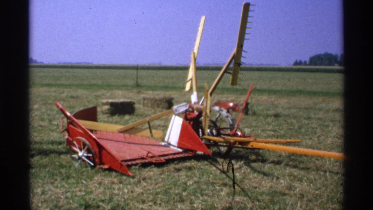 Hay rake and farm implement parts in an open field.