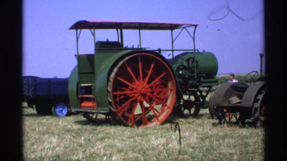 1971 Minnesota 8mm frame showing a green steam tractor with a large red spoked wheel and a small person partly visible nearby.