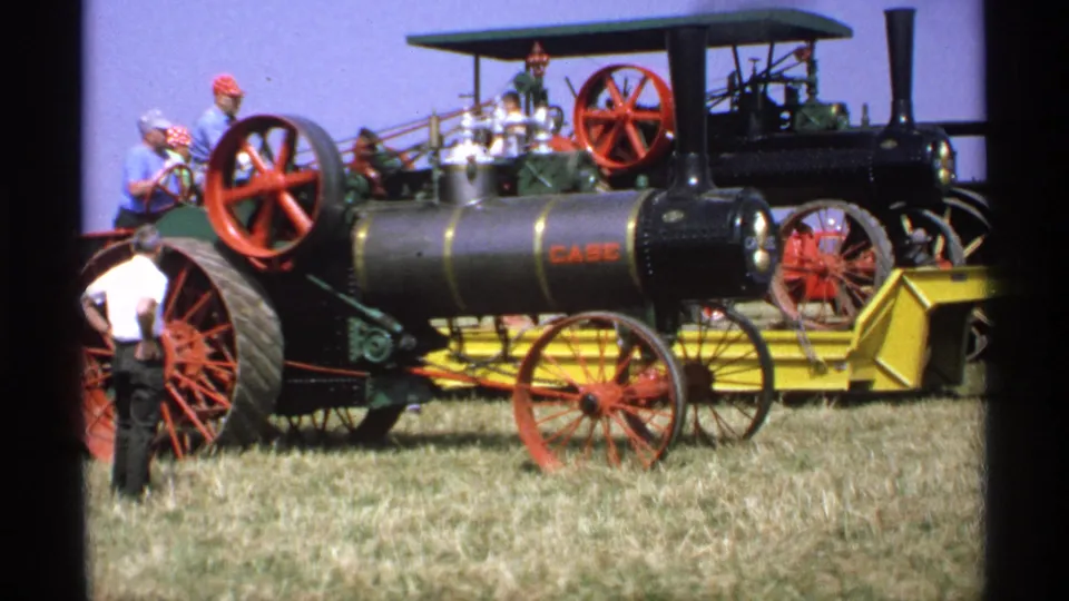 1971 Minnesota fair footage frame showing the Case steam tractor from the side with adults on and around the machine.