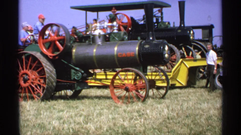 1971 Minnesota frame with a closer view of the Case steam tractor, red wheel, boiler, flywheel, and nearby fair visitors.