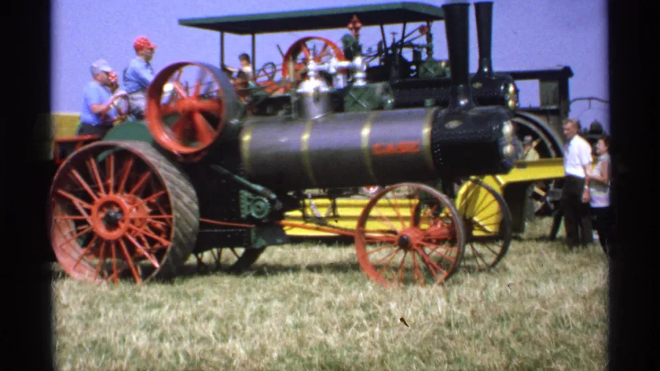 1971 Minnesota home-movie frame showing the Case steam tractor in profile with fairgoers nearby on a grassy field.