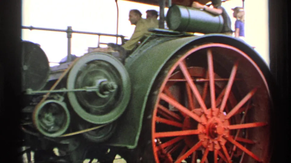 1971 Minnesota 8mm frame showing the green steam tractor, red spoked rear wheel, exposed side mechanism, and nearby fair visitors.