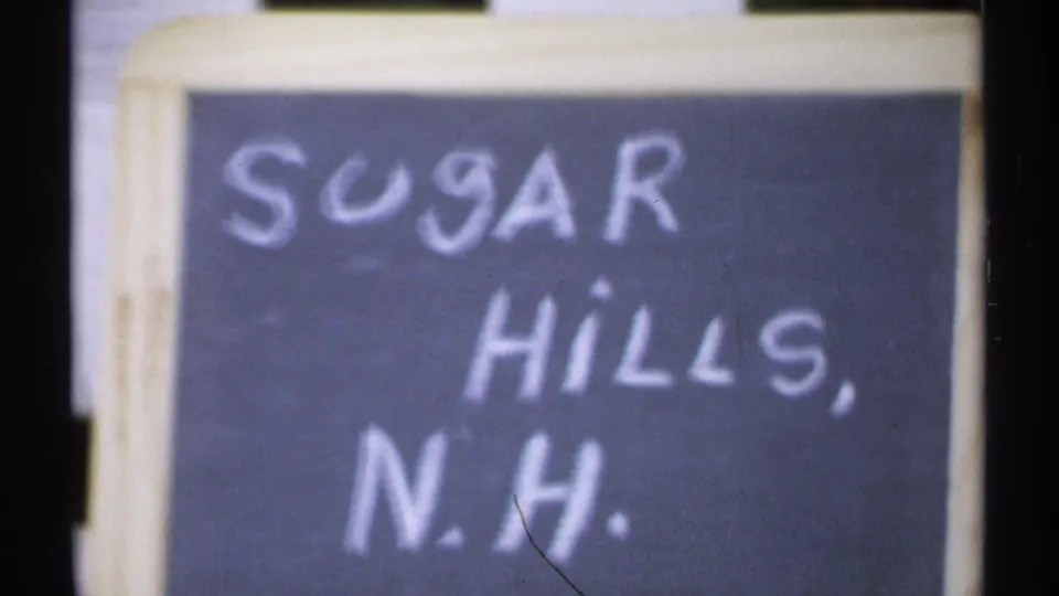 Hand-lettered Sugar Hills, N.H. sign seen close up in soft 8mm color.