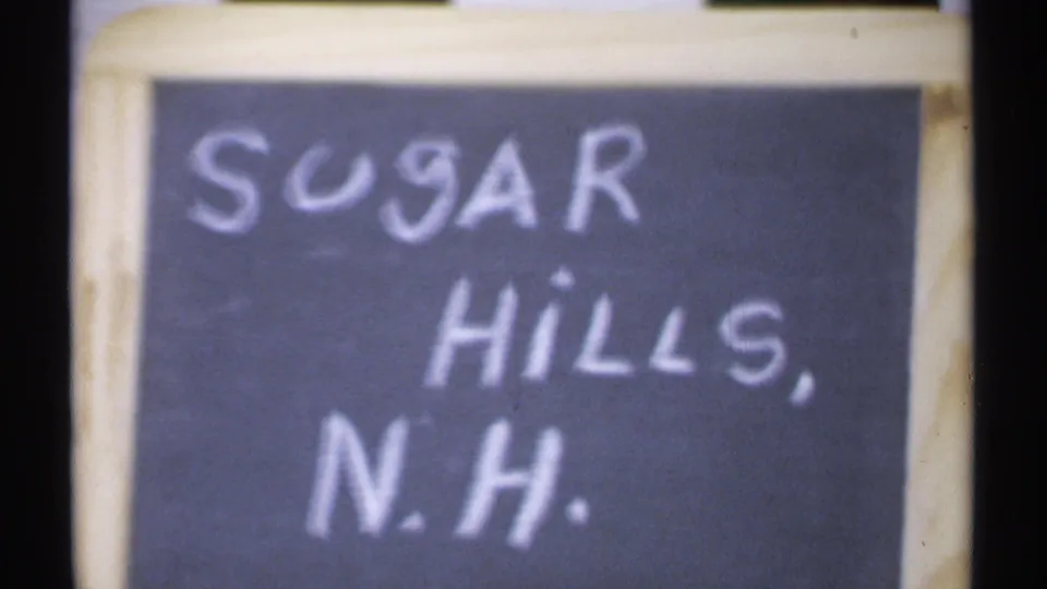 Soft close-up of the Sugar Hills, N.H. chalkboard sign from the home-movie sequence.