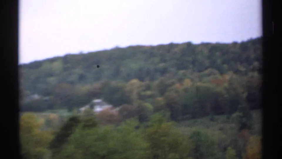 Rolling green hills and dense trees in New Hampshire, seen in soft 1971 8mm footage.