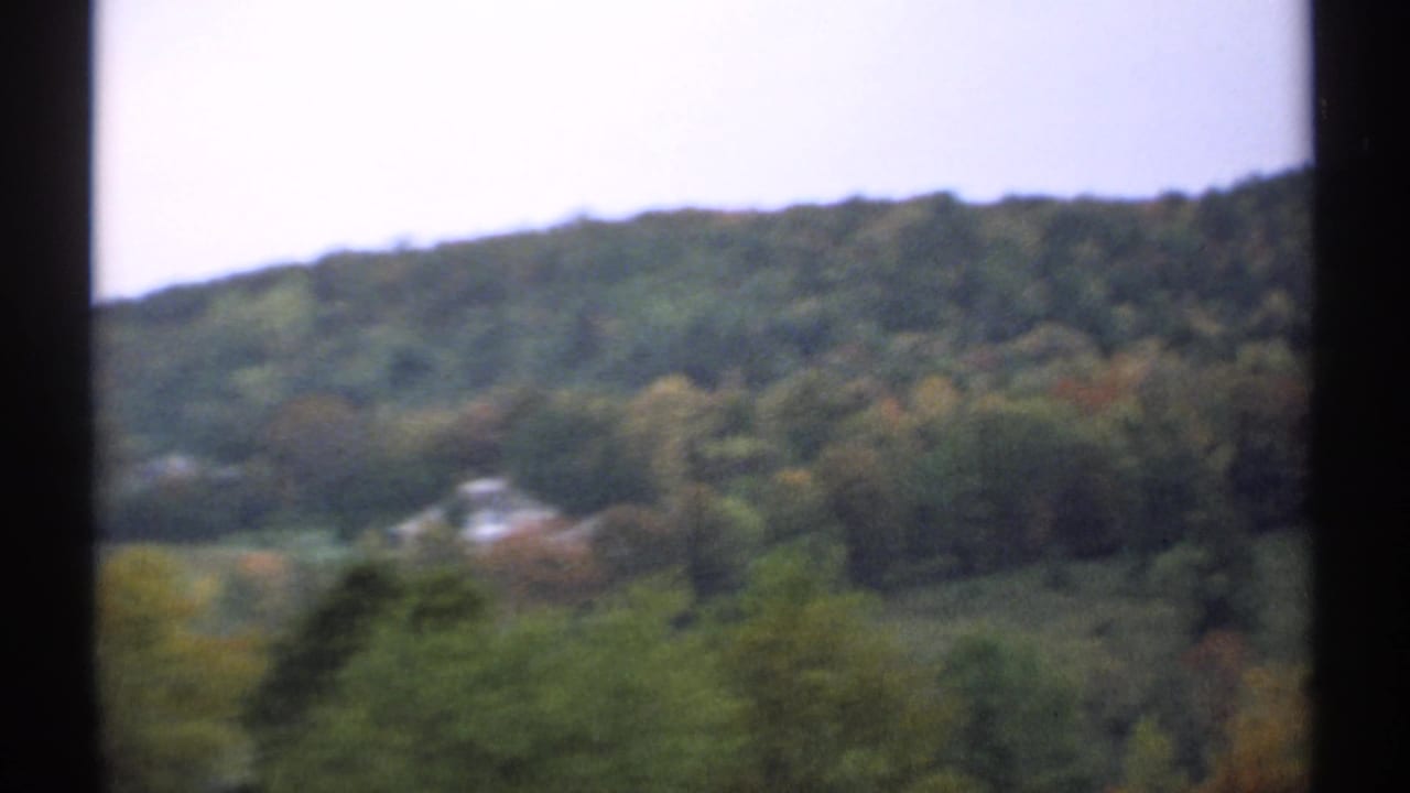 Soft view of wooded New Hampshire hills seen through dark vertical borders.