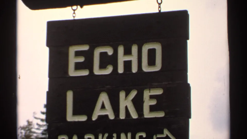 Close 1971 8mm view of a wooden Echo Lake Parking sign with white lettering and a right-pointing arrow.