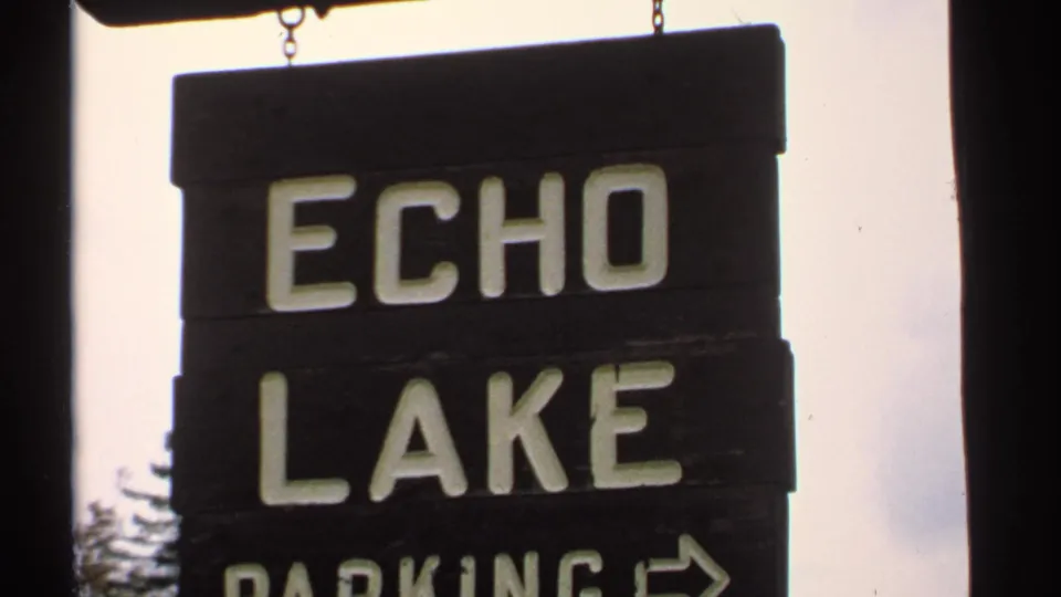 Close-up of the Echo Lake Parking sign in New Hampshire, with block letters, dark wood boards, and a directional arrow.