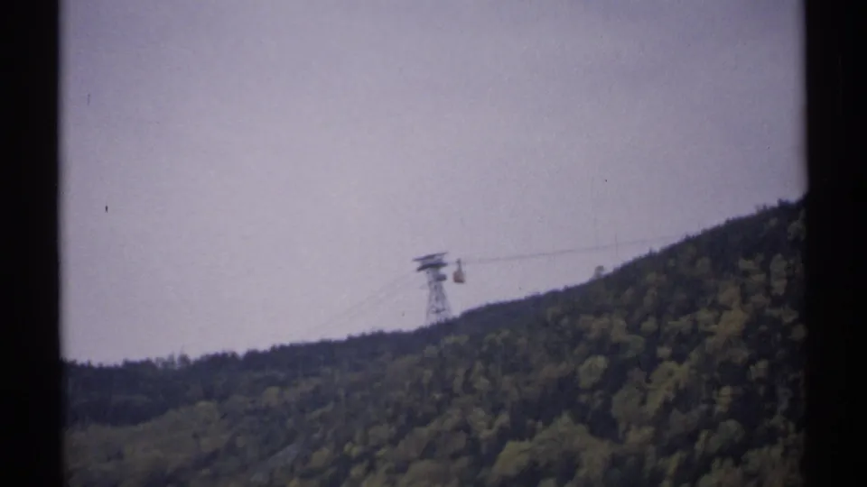 Soft 8mm footage frame of an aerial tramway crossing a forested New Hampshire mountain in 1971.