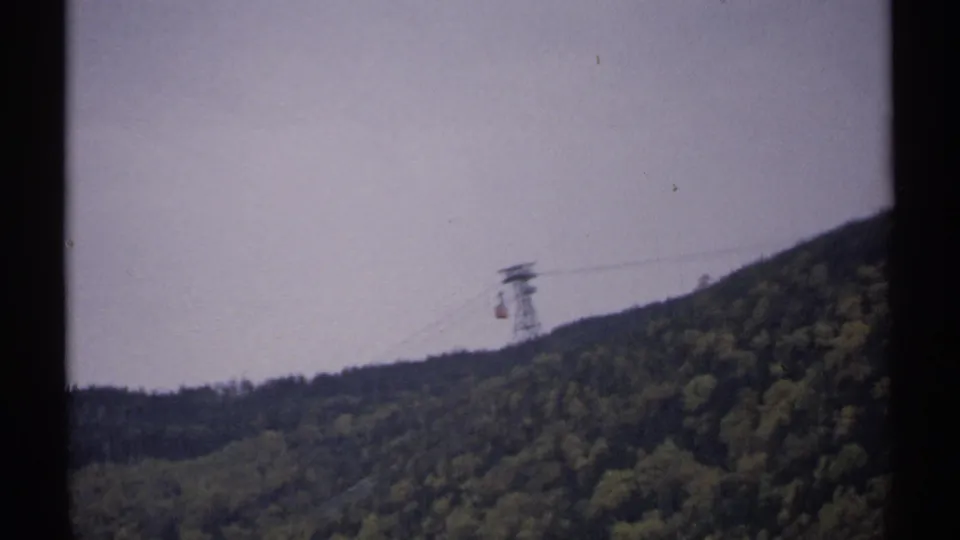 1971 New Hampshire 8mm frame showing a small red tram car near a support tower over a wooded mountain slope.