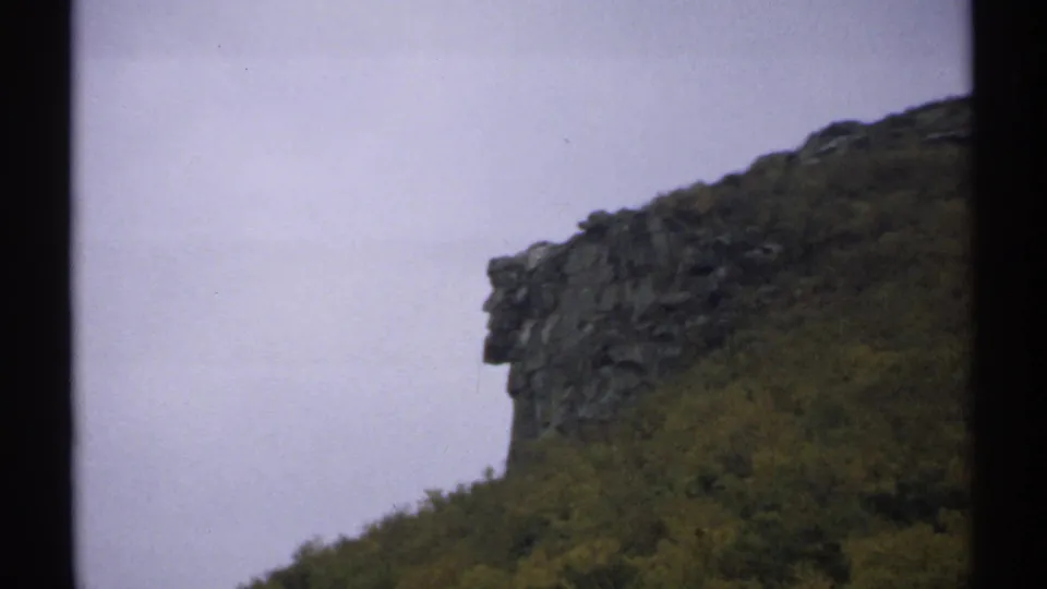 Distant 8mm view of the Old Man of the Mountains rock formation on a New Hampshire hillside in 1971.