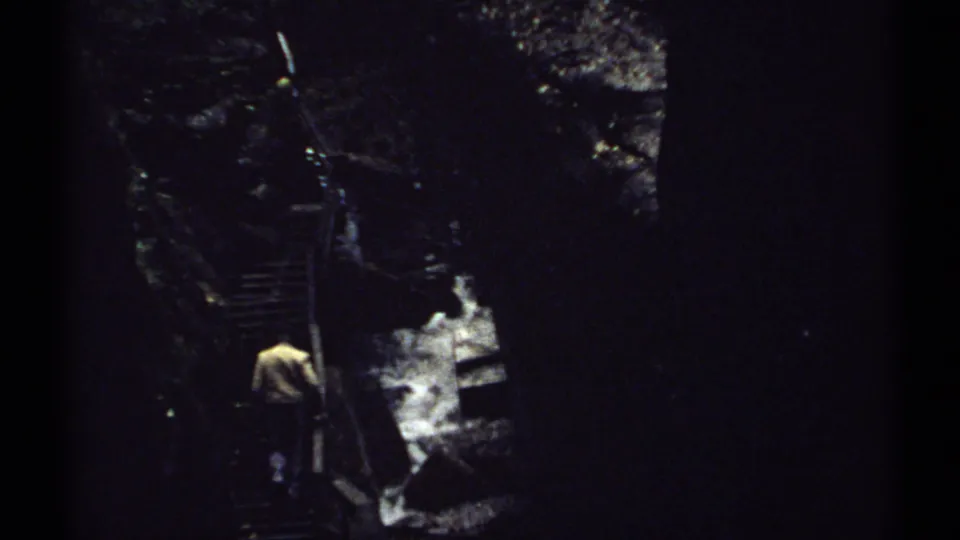 Rear view of a hiker climbing a steep stairway in a dark wooded ravine in New Hampshire, 1971.