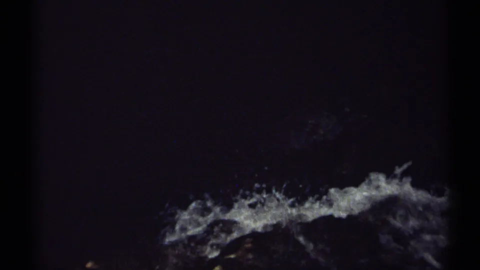 1971 New Hampshire 8mm frame with splashing waterfall flow across dark rocks, partly obscured by deep shadow and scan edge.
