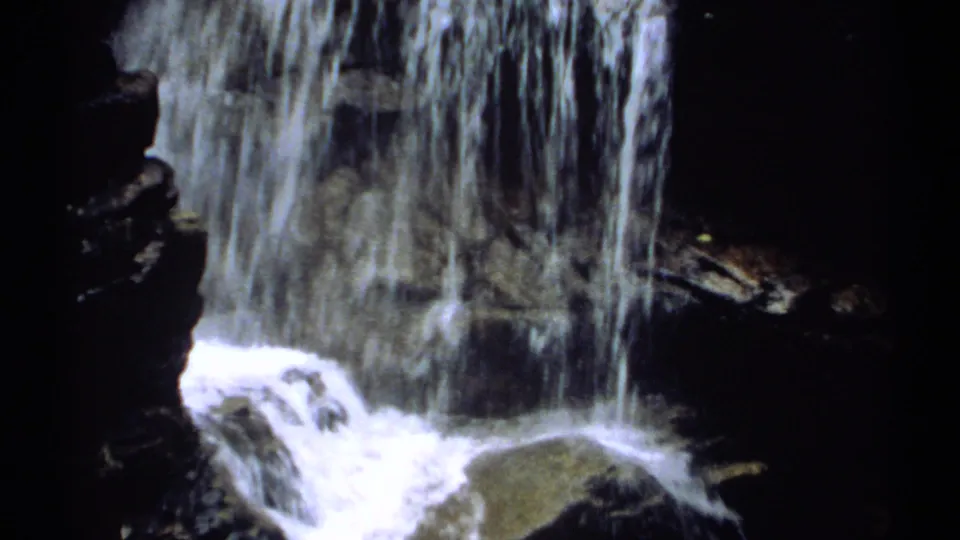 New Hampshire waterfall frame showing vertical white streams falling over dark rock into a lower rocky channel.