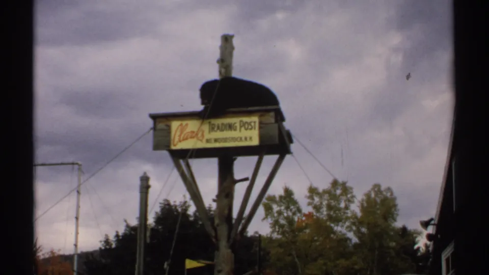 The bear remains perched on the Clarks Trading Post sign in a soft, grainy 1971 New Hampshire home-movie frame.