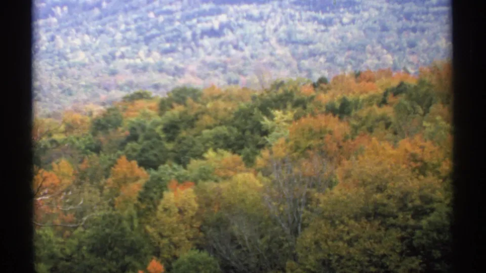 1971 New Hampshire 8mm view of fall-colored forest and distant hills framed by dark window borders.