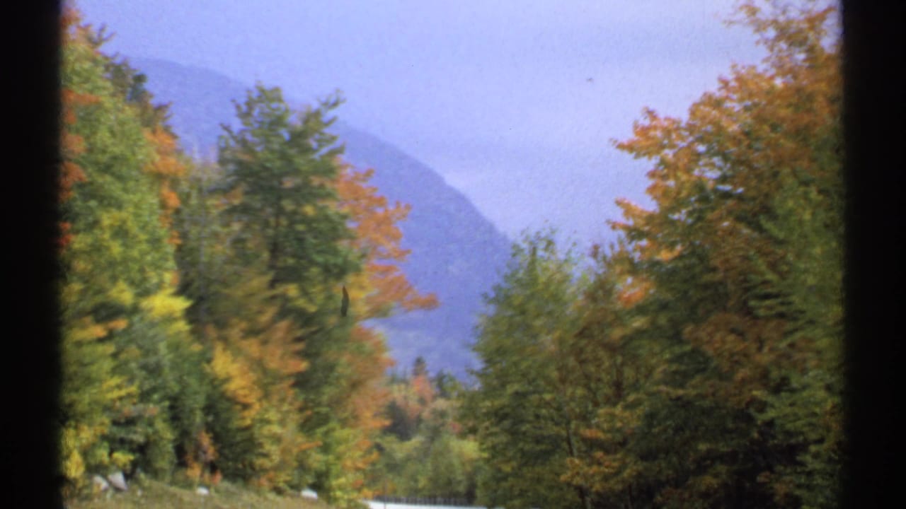 Autumn trees and distant mountains viewed through dark frame edges.