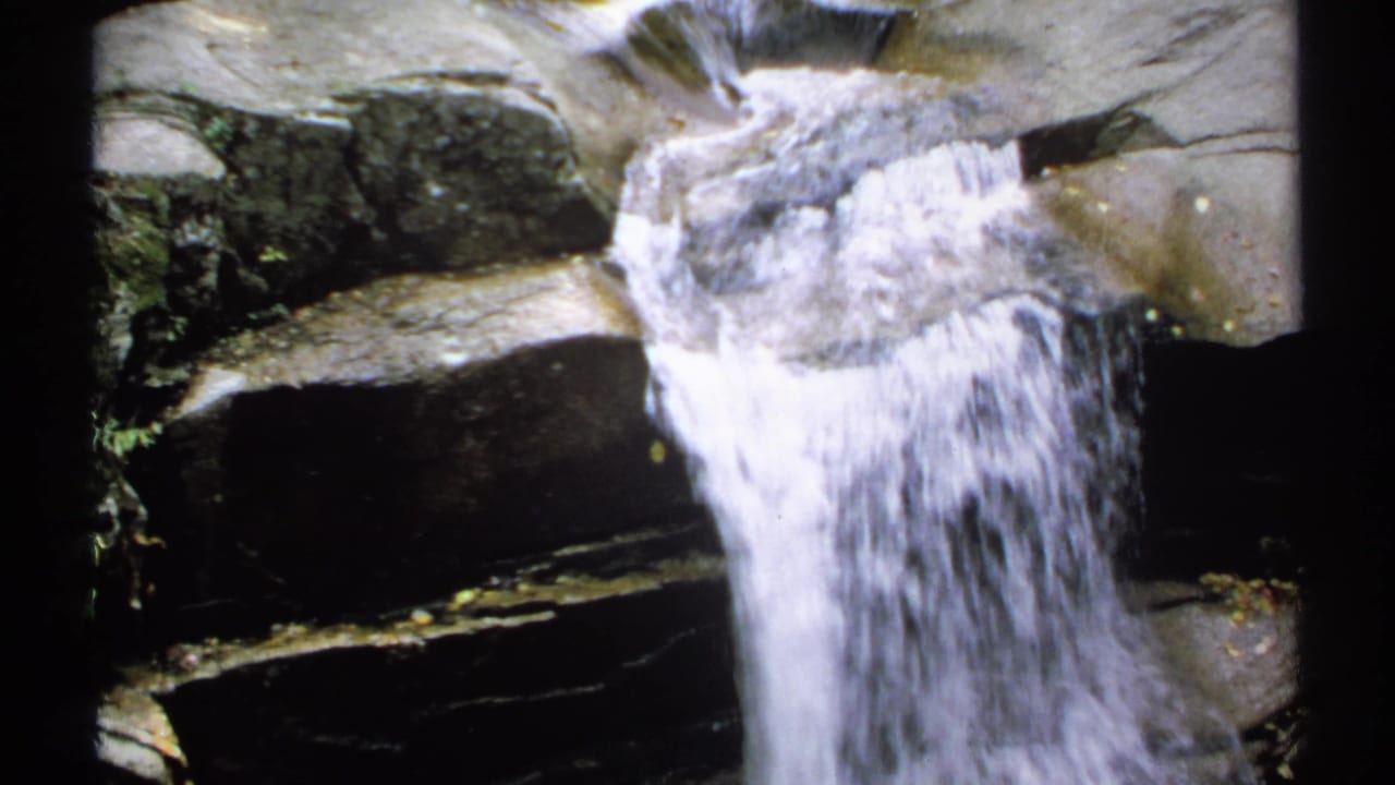 Small waterfall spilling over dark layered rocks.