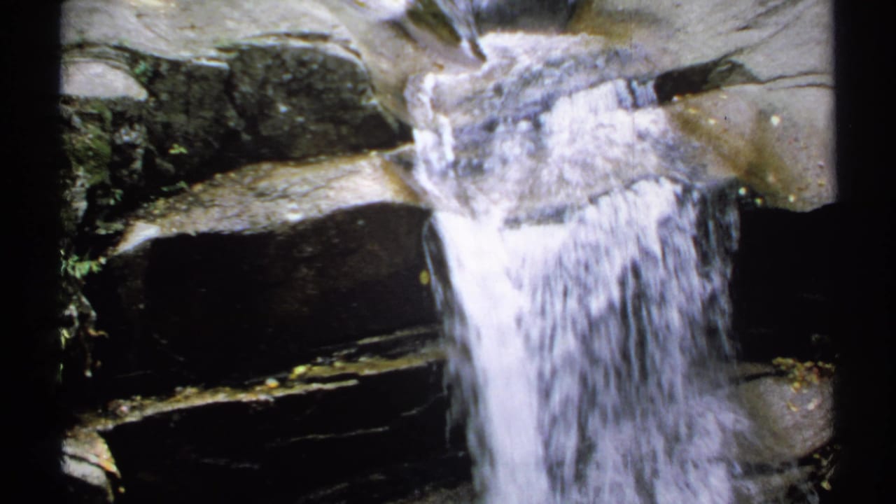 Clear water falls down a narrow rocky chute.