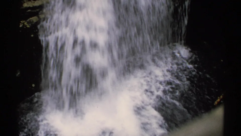 8mm home-movie frame from New Hampshire, 1971, showing white water cascading over dark rocks in a shaded woodland.