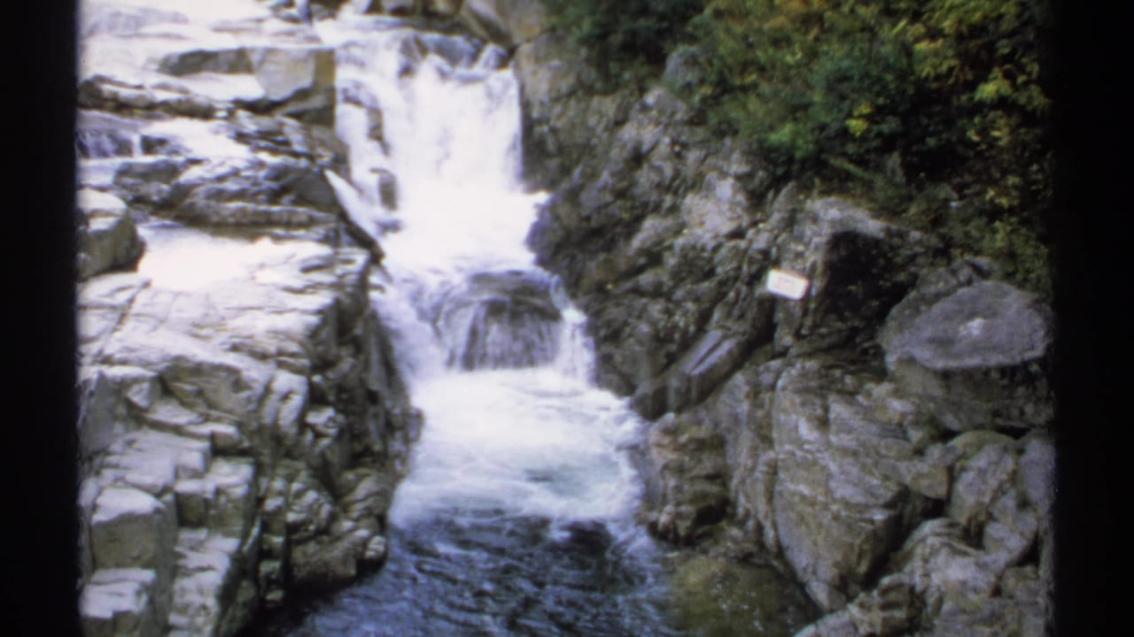 Rocky waterfall scene with a small sign beside the cascade.