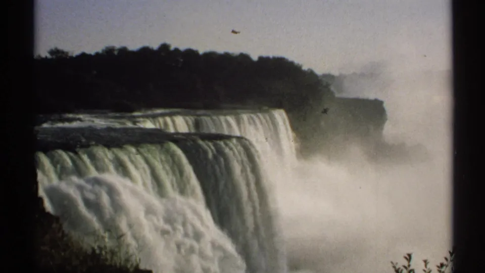 1971 8mm home-movie view of Niagara Falls in New York, showing water dropping over broad ledges into mist below.
