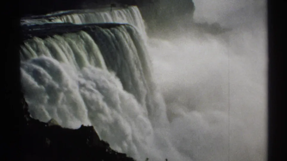End frame from the 1971 Niagara Falls clip, with foaming water plunging past a dark edge into a wide field of mist.